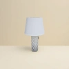 The white lampshade is paired with a black cylindrical lamp base featuring star-shaped patterns details Picture